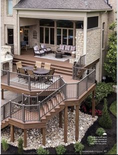 an outdoor deck with chairs and table next to a house that is built into the ground