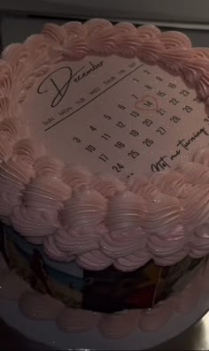 a large pink cake sitting on top of a table next to a microwave oven with writing on it