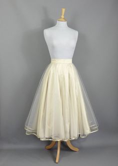 This show stopping skirt is made from a layer of Champagne coloured silk dupion with two layers of tulle hemmed in Gold trim. The tulle layers are a double circle which means lots and lots of volume! Wear with a 'Swing' petticoat for extra swish on the dance floor! Seen in the last photo without a petticoat underneath. The skirt is designed to be worn quite high on the waist and has a snug fitting waistband so please check your own measurement against our standard sizes before ordering. This skirt can be made in a range of standard sizes or can be made to fit your exact waist measurement if you are inbetween sizes for no extra cost. Size UK 6 is made to fit Waist 24/5"  Size UK 8 is made to fit Waist 26/27"  Size UK 10 is made to fit Waist 27/28"  Size UK 12 is made to fit Waist 29/30"  Si Party Full Crinoline Skirt, Elegant Tiered Crinoline Skirt, Elegant Voluminous Tulle Petticoat, Silk Wedding Skirt For Summer, Summer Wedding Silk Skirt, Elegant Tulle Tiered Skirt Petticoat, Sheer Organza Evening Skirt, Elegant Tiered Tulle Petticoat, Long Organza Tulle Skirt