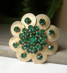 Beautiful vintage emerald green rhinestone floral pin. This vintage brooch is comprised of all emerald green rhinestones on goldtone metal in a round floral design.  Rivet back with prong-set rhinestones. Circa-1950's.  Roll-over clasp works great.  Approx. 2" across. No discolored, loose, or missing stones.  In fantastic shape! Sorry, but no international shipping at this time. Please see my shop for more vintage, estate jewelry: nightowlmemories.etsy.com Cheap Green Flower Brooches, Vintage Green Brooch Jewelry, Antique Green Brooch For Anniversary, Antique Green Brooches For Anniversary, Green Jeweled Brooch For Gift, Green Jeweled Brooches As Gift, Green Jeweled Brooch Gift, Green Jeweled Brooches For Gifts, Antique Green Brooches For Wedding