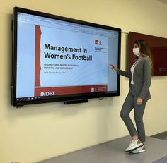 a woman standing in front of a flat screen tv with the words management in women's football on it