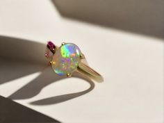 Discover our stunning 14k Gold Australian Crystal Opal Ring, sourced from Lightning Ridge, Australia. Experience its enchanting play-of-color. Origin- Lightning Ridge Australia. Opal Weight- 1ct Australian Crystal Opal Setting- 14k Gold Claw Setting Accent Stone- Pink Sapphire Ring Size- 6 1/2us - Complimentary resizing if required, add a note at checkout! Handcrafted and designed by Australian Artisans Opal And Sapphire Ring, Opal Wedding Band, Lightning Ridge Opal, Pink Sapphire Ring, Australian Boulder Opal, Claw Setting, Crystal Opal, Rustic Jewelry, Lightning Ridge