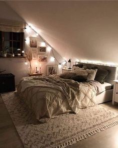 an attic bedroom with lights on the ceiling and a bed covered in blankets, pillows and blankets