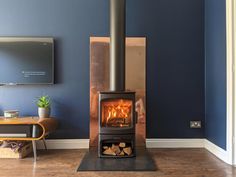 a wood burning stove in a living room with blue walls and hardwood flooring on the side