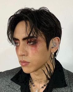 a close up of a person with makeup and piercings on his face, wearing a suit