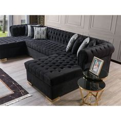 a living room with black couches and pillows on top of the couch is next to a coffee table