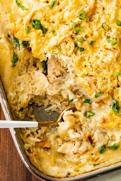 a casserole dish with chicken, rice and green onions in it on a wooden table