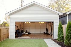 a white garage with an open door on the outside and grass in the front yard