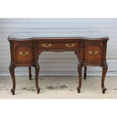 an antique desk with glass top and gold trimmings on the legs, sitting in front of a garage door