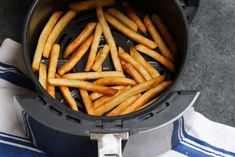 french fries being cooked in an air fryer on top of a blue and white towel