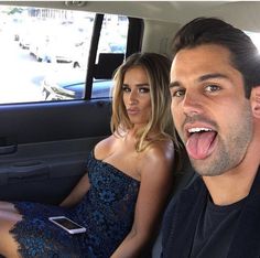 a man and woman sitting in the back seat of a car with their tongue out