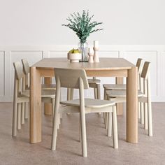 a wooden table with chairs around it and a vase filled with flowers on the table