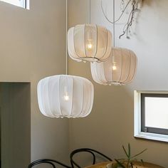 three white lanterns hanging from the ceiling above a table