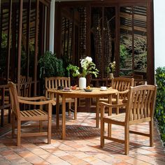 an outdoor dining area with wooden furniture and plants on the table, surrounded by greenery