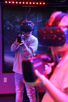 two people standing in front of a screen with virtual glasses on their heads and one person holding a camera