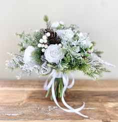 a bridal bouquet with white flowers and pine cones