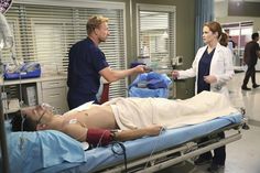 a man laying on top of a hospital bed next to a woman in scrubs