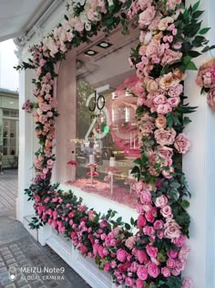 a window display with pink flowers and greenery