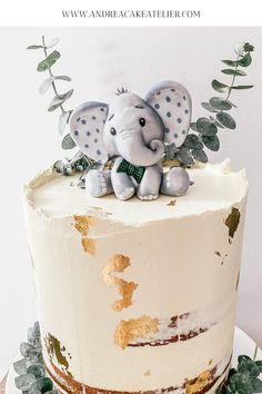 an elephant figurine sitting on top of a white cake with gold leaf decorations