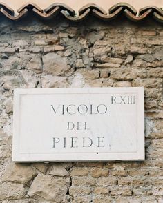 a sign that is on the side of a brick building with a tile roof above it