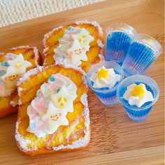 several pieces of bread with icing and sprinkles on them next to plastic cups