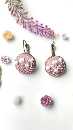 two pink earrings with flowers and leaves on them