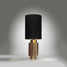 a table lamp with a black shade on the top and gold trim around the base