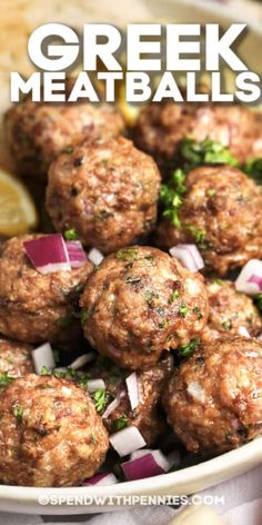 greek meatballs with onions and herbs in a white bowl on a table next to pita bread