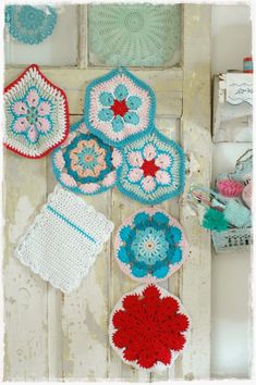 several crocheted doily are hanging on a wooden door with other items in the background