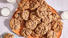 an orange plate topped with cookies next to milk