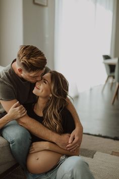 a man and woman sitting on top of a couch hugging each other in the living room