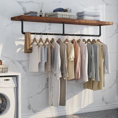 clothes hanging on a rack next to a washer and dryer in a room