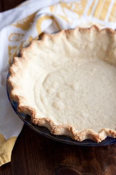 an uncooked pie sitting on top of a wooden table next to a napkin