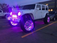 a white jeep parked in a parking lot with purple lights on it's tires