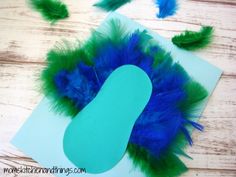 blue and green feathers on top of a piece of paper