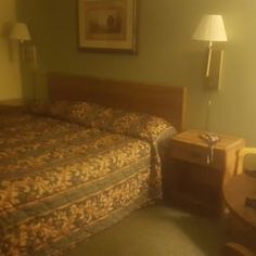 a bed room with a neatly made bed next to a night stand and two lamps