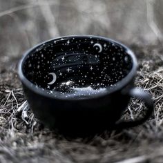 a black cup sitting on top of dry grass covered in drops of water and stars