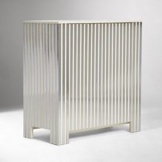 a white cabinet sitting on top of a floor next to a gray wall with vertical stripes