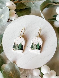 the earrings are decorated with green leaves and mountains