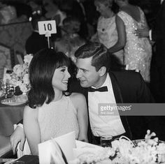 an old black and white photo of two people sitting at a table in formal wear