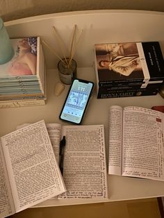 an open book sitting on top of a table next to a cell phone and books