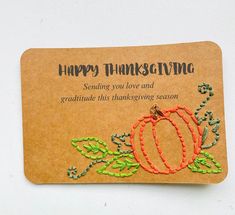 a thanksgiving card with an orange pumpkin and green leaves on the front, sitting on a piece of brown paper