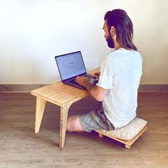 a man sitting at a table with a laptop on it's lap and looking at the screen