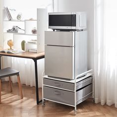 a microwave on top of a refrigerator in a room with wooden floors and white walls