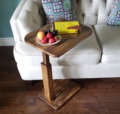 a small table with fruit on it in front of a white couch and blue wall