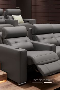 a row of grey leather recliners sitting on top of a wooden floor