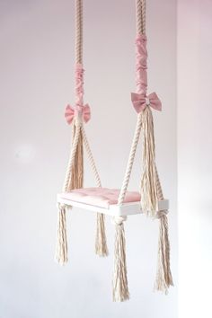 a pink and white swing with tassels hanging from it's sides in a room