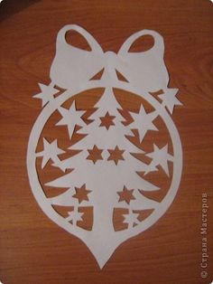 an ornament with stars and a bow is cut out on a wooden surface