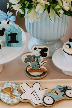 mickey mouse cookies are sitting on a tray next to some flowers and other decorative items