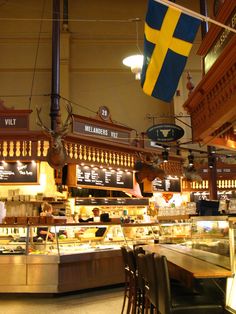 the inside of a restaurant with flags hanging from the ceiling and tables in front of it